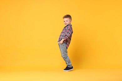 Photo of Happy little boy dancing on yellow background