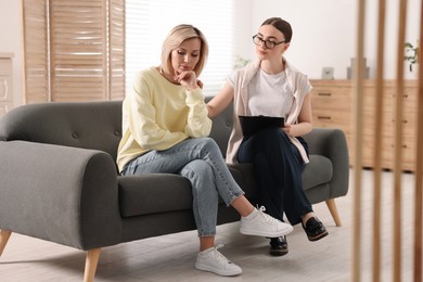 Photo of Professional psychotherapist working with on sofa patient in office