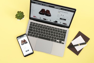 Photo of Online store website on laptop screen. Computer, smartphone, stationery and houseplant on beige background, flat lay