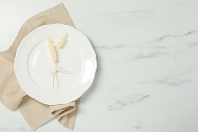 Photo of Elegant plate with spikes and napkin on white marble table, top view. Space for text