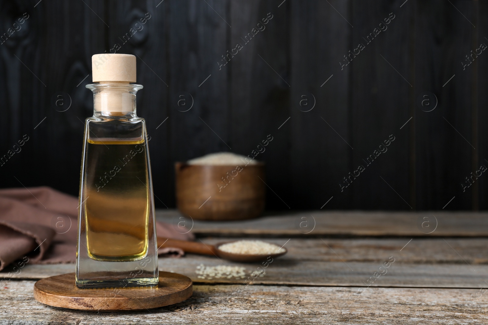 Photo of Bottle of organic sesame oil on wooden table. Space for text