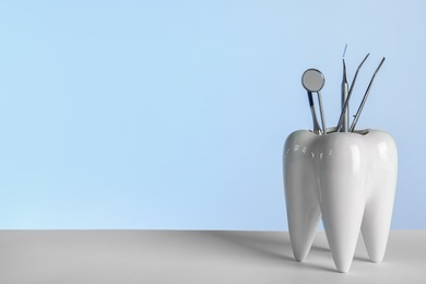 Photo of Tooth shaped holder with professional dentist tools on grey background. Space for text