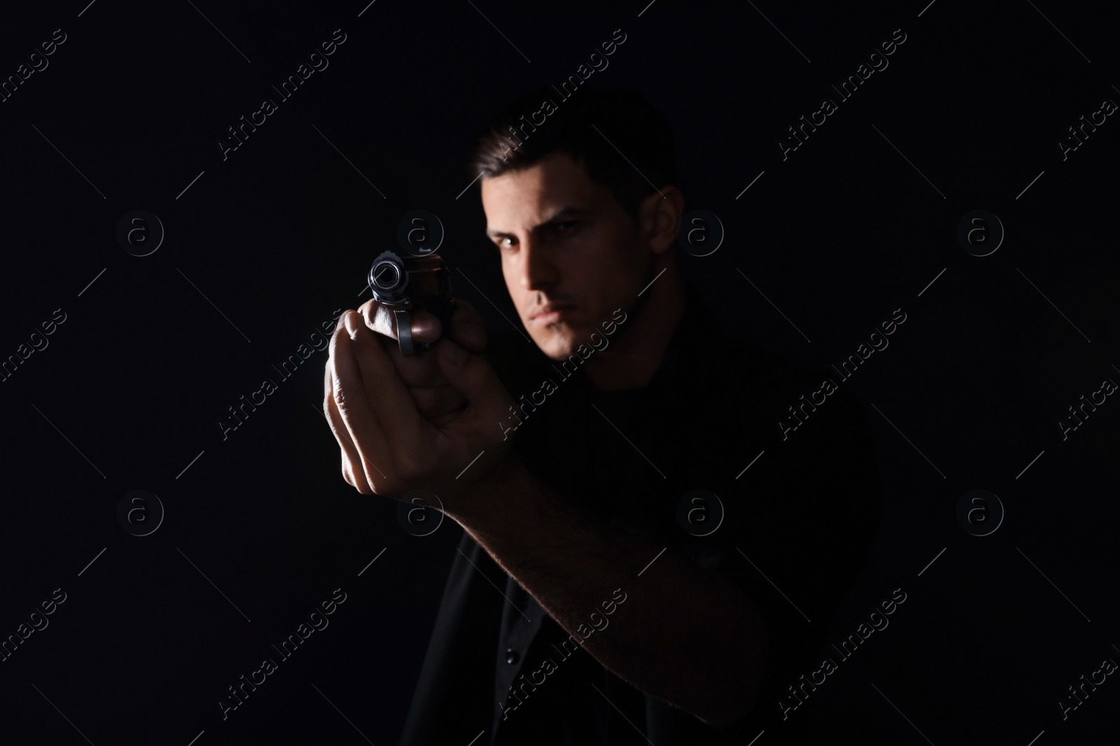 Photo of Professional killer with gun on black background