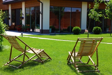 Wooden deck chairs in beautiful garden on sunny day