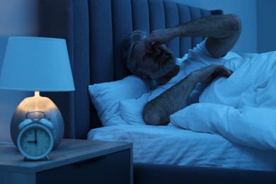 Mature man suffering from headache in bed at night