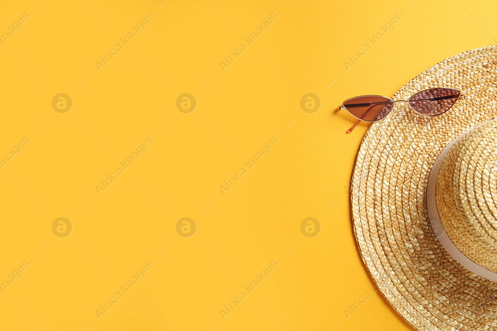 Photo of Hat and sunglasses on yellow background, flat lay with space for text. Sun protection accessories