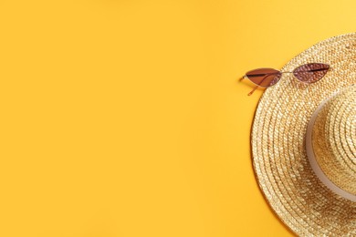 Hat and sunglasses on yellow background, flat lay with space for text. Sun protection accessories