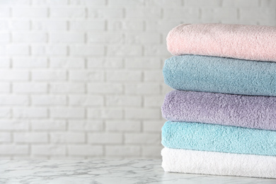 Stack of clean bath towels on white marble table. Space for text