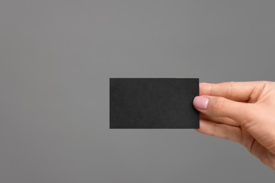 Photo of Woman holding blank business card on grey background, closeup. Space for text