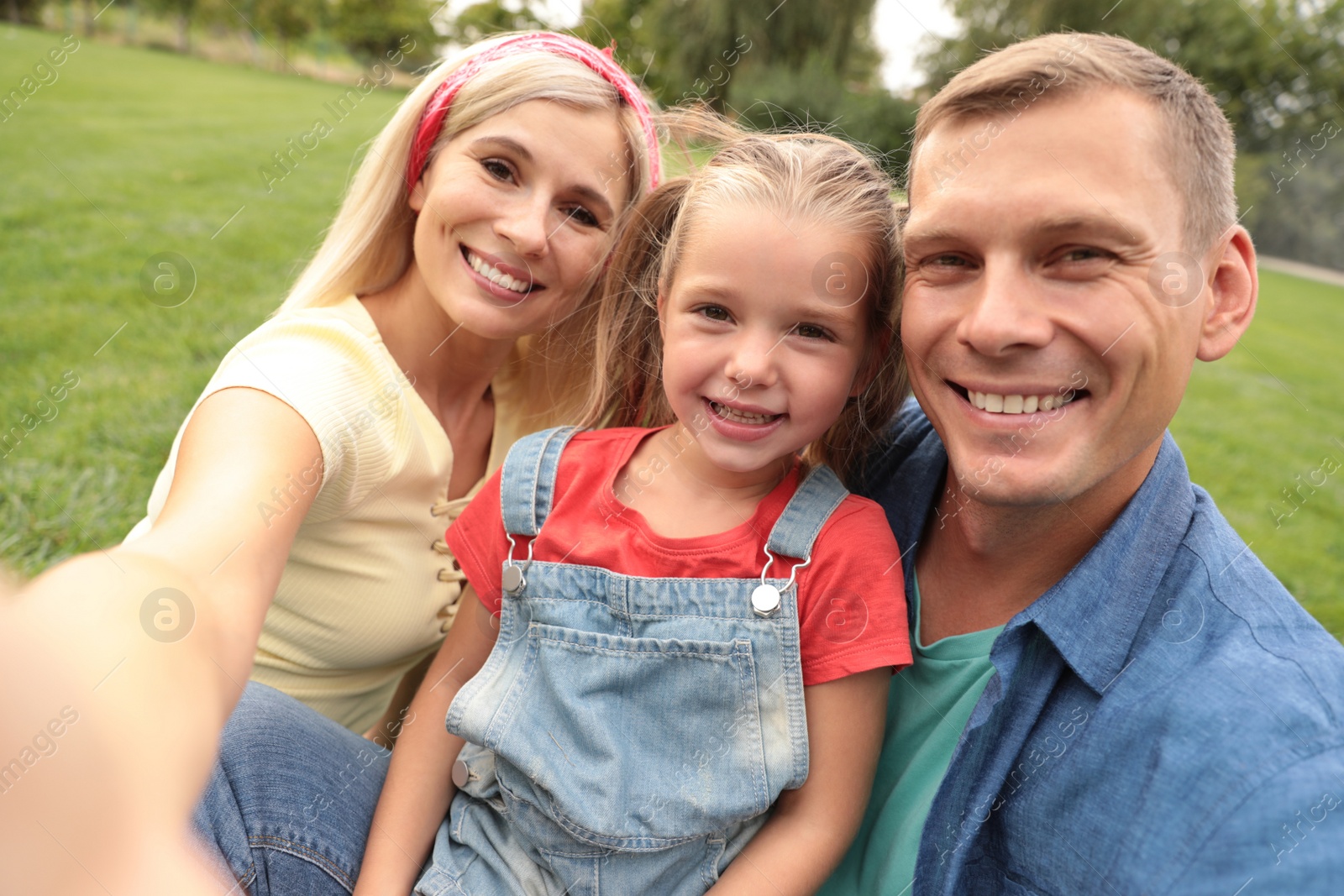 Photo of Happy family taking selfie in park on summer day