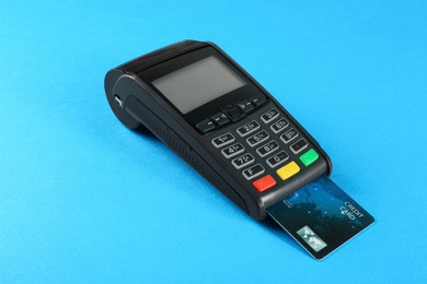 New modern payment terminal with credit card on light blue background