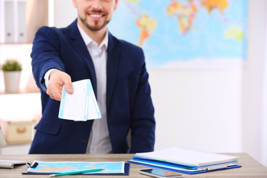 Photo of Male consultant holding tickets in travel agency, closeup. Space for text