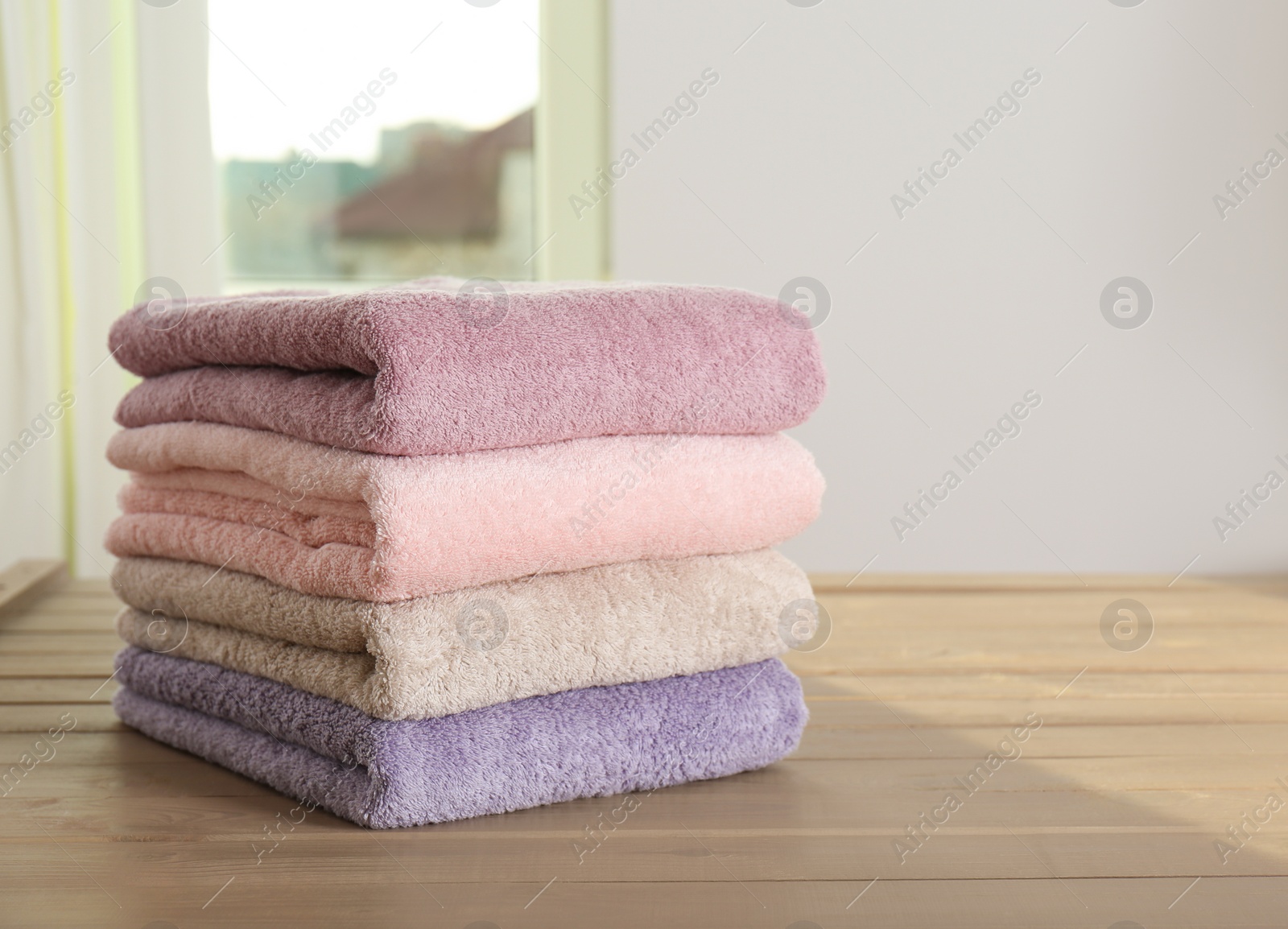 Photo of Stack of color towels on wooden table in bathroom
