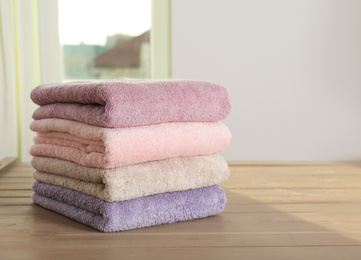 Photo of Stack of color towels on wooden table in bathroom