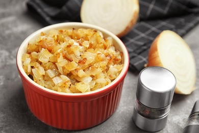 Tasty fried onion and pepper shaker on grey table, closeup
