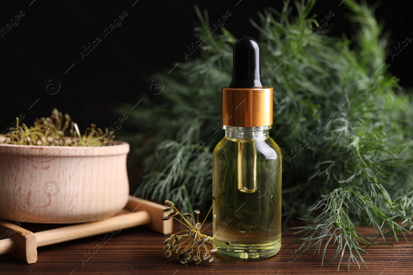 Photo of Bottle of essential oil and fresh dill on wooden table