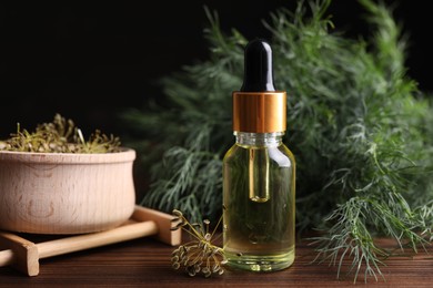 Bottle of essential oil and fresh dill on wooden table