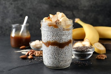 Photo of Delicious chia pudding with banana, walnuts and caramel sauce on black table