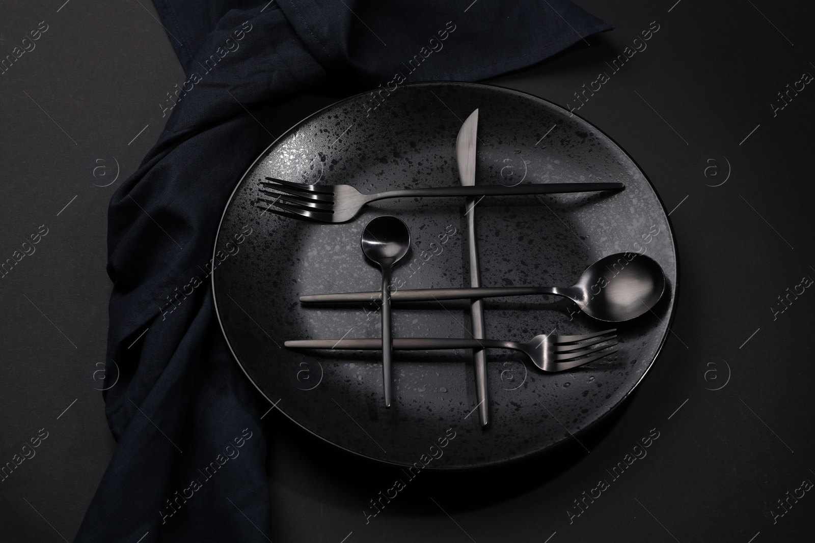 Photo of Stylish table setting. Plate, napkin and cutlery on black background