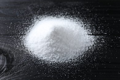 Photo of Pile of organic salt on black wooden table, closeup