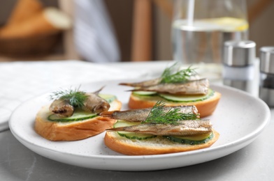 Photo of Delicious sandwiches with sprats, cucumbers and dill on light table