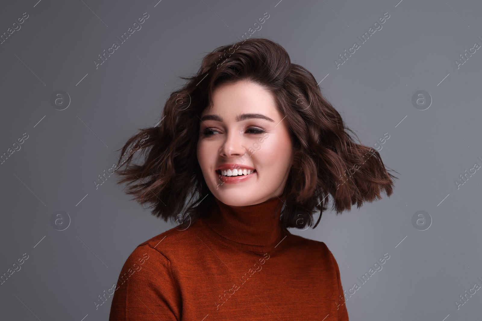 Photo of Portrait of beautiful young woman with wavy hairstyle on grey background