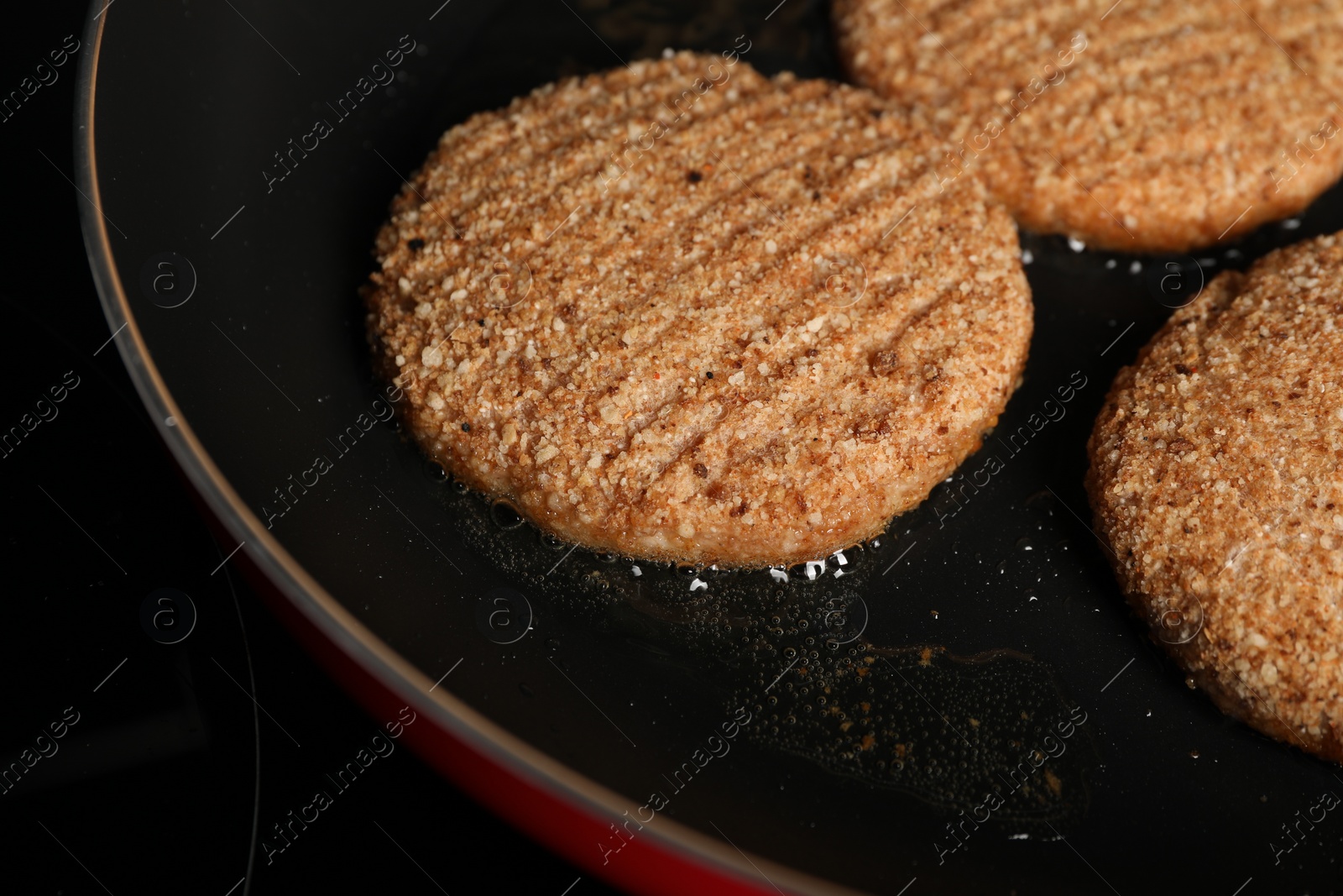 Photo of Cooking vegan cutlets in frying pan on cooktop, closeup