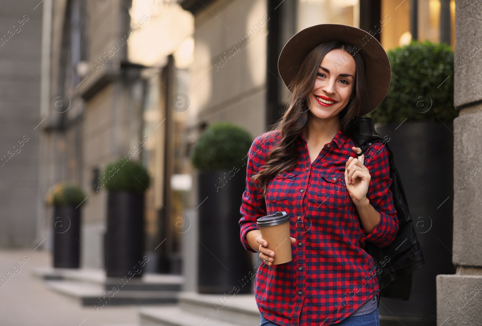 Photo of Beautiful woman with cup of coffee on city street. Autumn walk