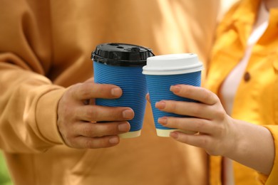 Photo of Couple with takeaway coffee cups outdoors, closeup