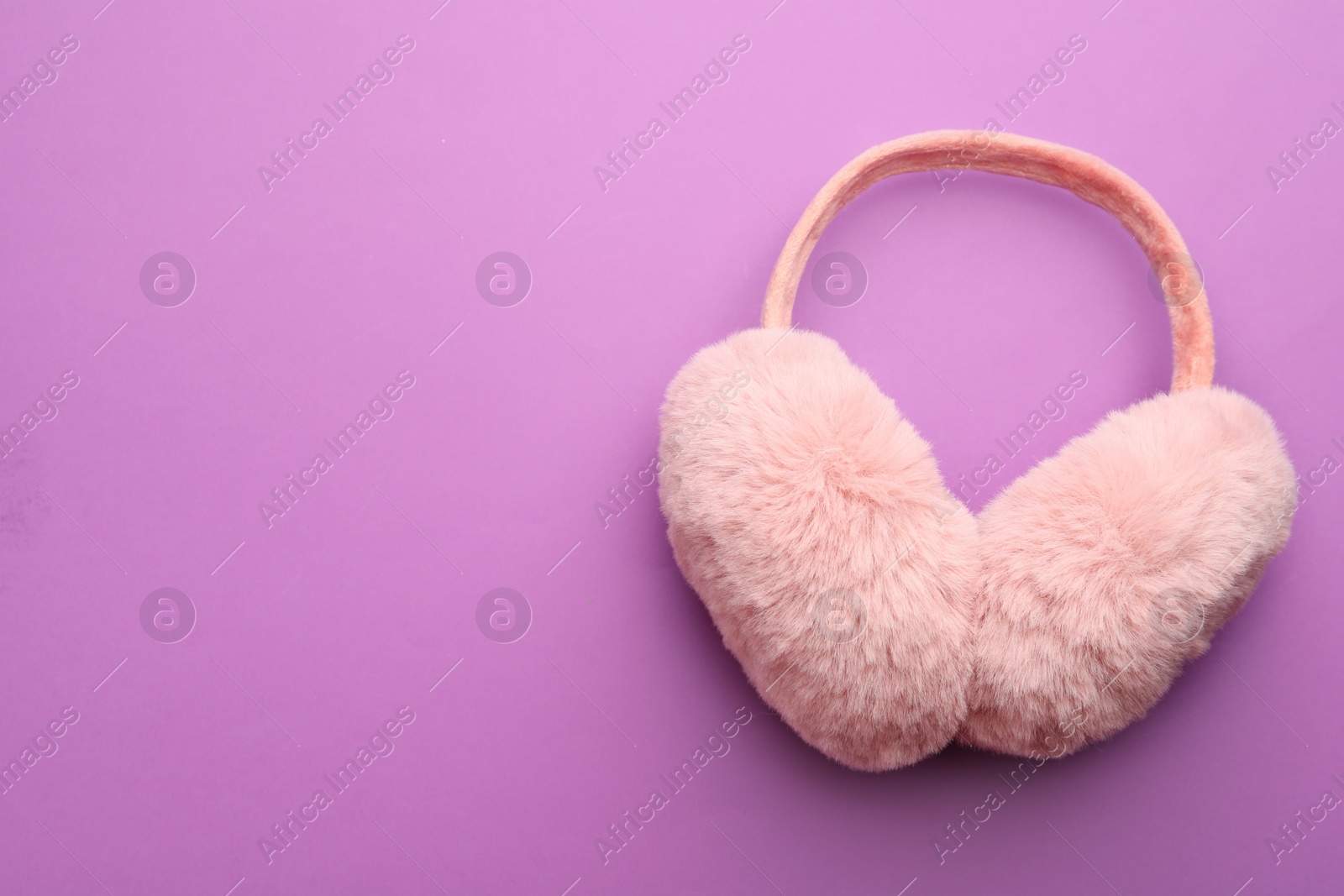 Photo of Stylish winter earmuffs on purple background, top view. Space for text