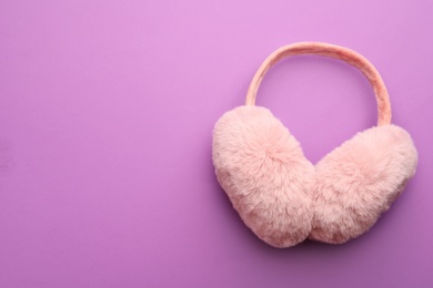 Stylish winter earmuffs on purple background, top view. Space for text