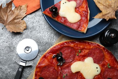 Cute Halloween pizza with ghosts and spiders served on grey table, flat lay