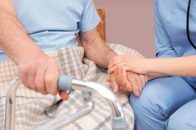 Nurse holding senior patient's hand in hospital, closeup. Medical assisting