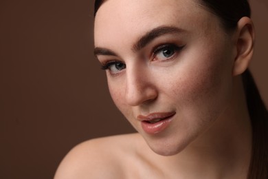 Portrait of beautiful woman with fake freckles on brown background, closeup