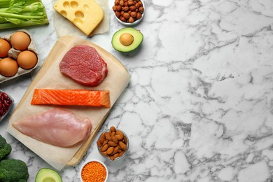 Photo of Different fresh products on white marble table, flat lay and space for text. Sources of essential amino acids