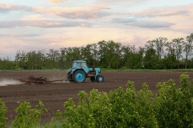 Photo of Tractor plowing agricultural field under cloudy sky