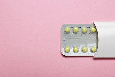 Photo of Birth control pills on pink background, top view. Space for text