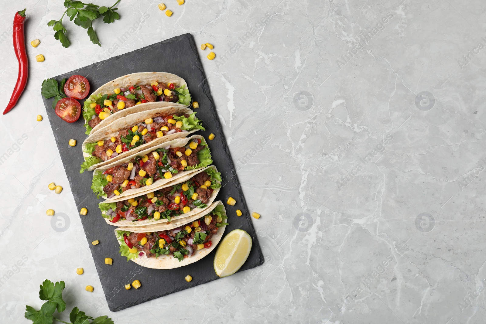 Photo of Delicious tacos with meat, vegetables and lime on light gray marble table, flat lay. Space for text