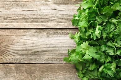 Photo of Fresh coriander on wooden table, top view. Space for text