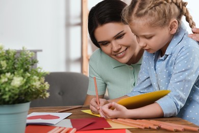 Cute little girl with her mother making beautiful greeting card at home