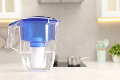 Photo of Water filter jug on light grey table in kitchen, space for text