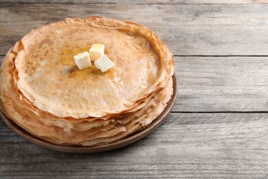 Photo of Stack of delicious crepes with melting butter on wooden table. Space for text