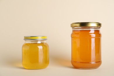 Photo of Jars with different types of organic honey on beige background