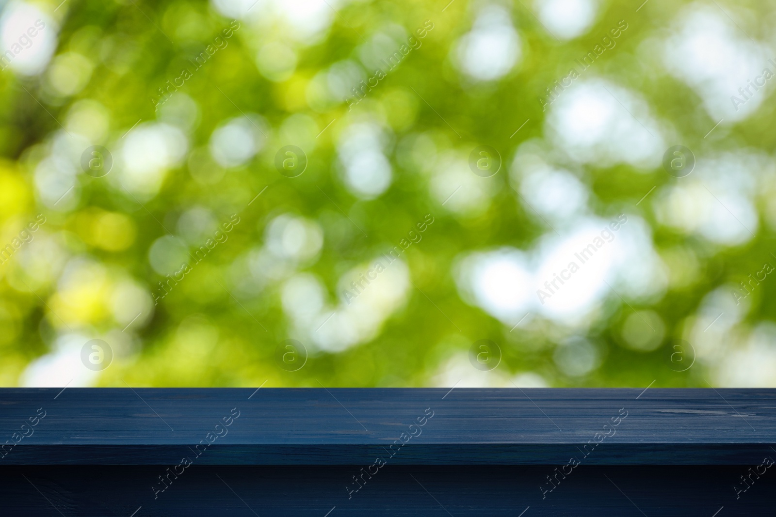 Image of Empty blue wooden surface against blurred green background. Space for design