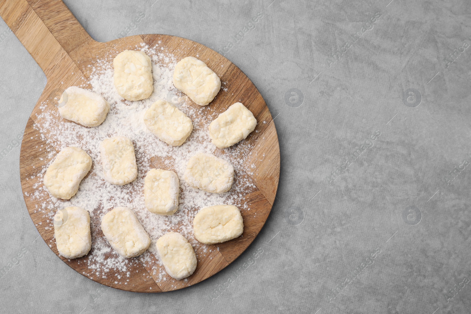 Photo of Making lazy dumplings. Board with cut dough and flour on grey table, top view. Space for text