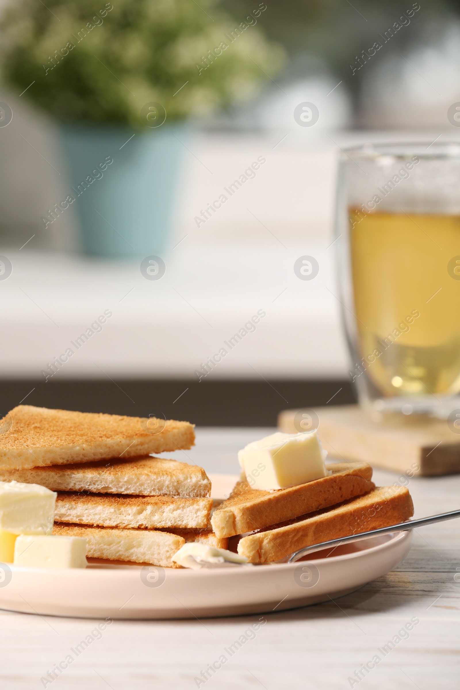 Photo of Tasty toasts with butter served on white wooden table