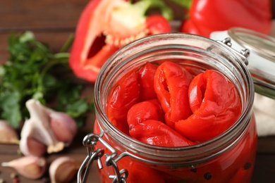 Photo of Glass jar with pickled peppers on table, closeup