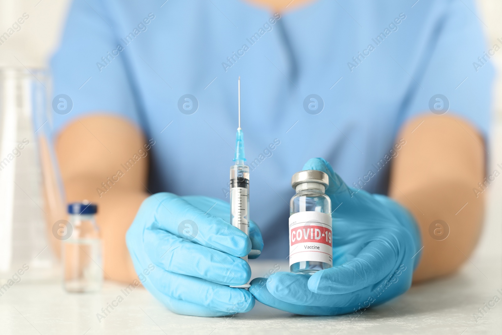 Photo of Doctor with coronavirus vaccine at table in laboratory, closeup