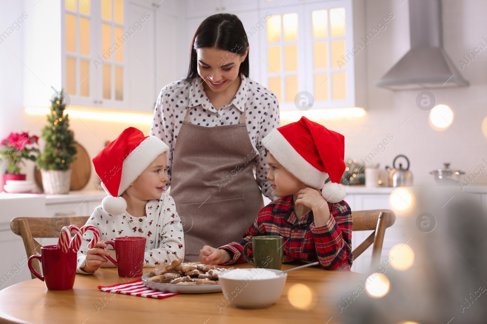 Photo of Mother and her cute little children with Christmas cookies in kitchen