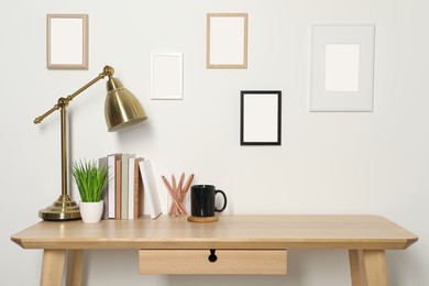 Photo of Comfortable workplace with wooden desk near white wall